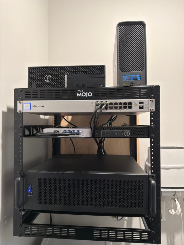 Black server chassis mounted in the lower rack, with cabled network equipment and shelf-mounted devices above.